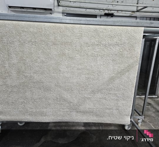שטיח תלוי לייבוש על מתקן מתכת